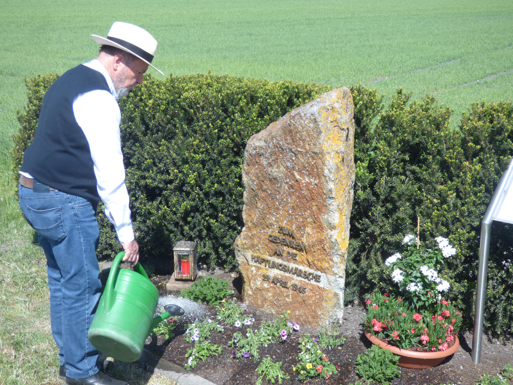 Zuvor hatte das Ehepaar Frombeck die Bepflanzung vor dem Gedenkstein hergerichtet. Das Foto zeigt Günther Frombeck beim Gießen.